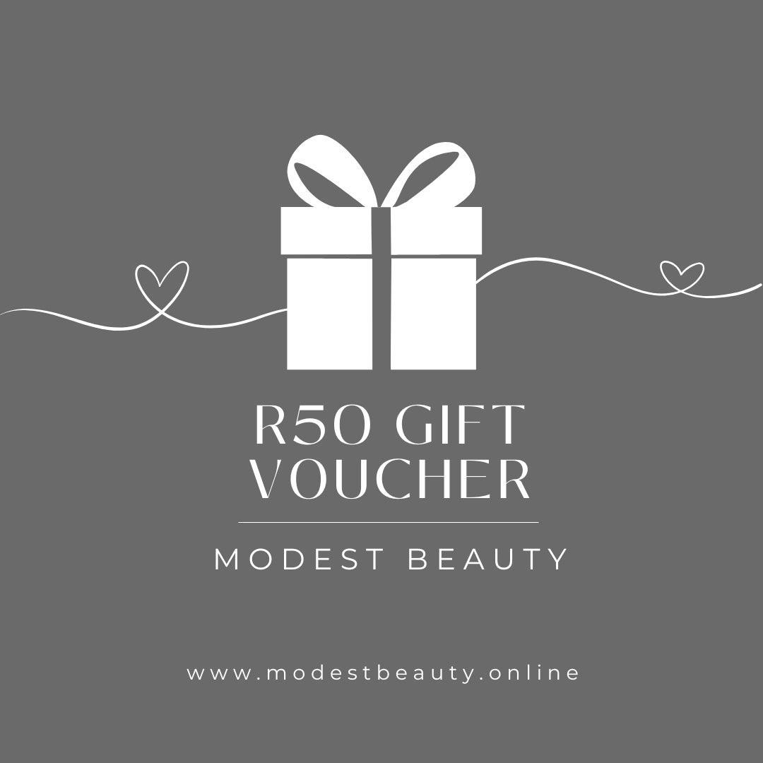 A minimalist graphic of a white gift box with a ribbon on a grey background. Below the gift box, text reads "Gift Voucher" and "Modest Beauty." A line with two hearts extends horizontally. The bottom of the image displays the website "www.modestbeauty.online," promoting luxury self-care.